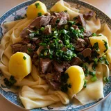 Бешбармак: куски говядины на широкой лапше с картофелем и зелёным луком